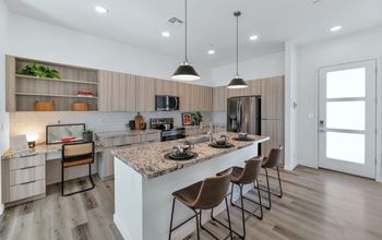 A modern kitchen with a marble countertop and wooden flooring.